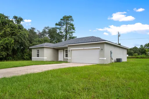 Single-story listing home with a green lawn under a blue sky